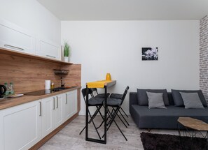 Eine moderne Küche mit weißen Schränken, einer Holzarbeitsplatte und einem schwarzen Stuhl an einem kleinen Tisch mit einer gelben Tischdecke.