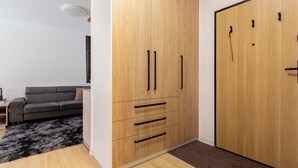 Una habitación moderna con un armario de madera, un sofá gris y una pequeña mesa.