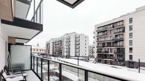 Un balcón con vistas a modernos edificios de apartamentos, una puerta de cristal y una barandilla de metal.