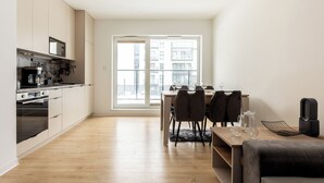 Una cocina moderna equipada con microondas, estufa y cafetera. Hay una zona de comedor con mesa y sillas, y un sofá.