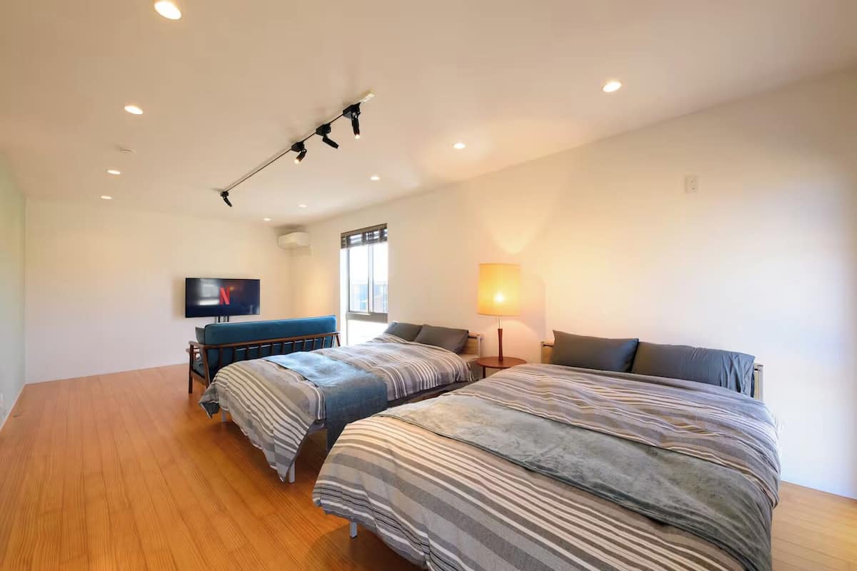 A hotel room with two beds, a TV, a lamp, and a ceiling light fixture.