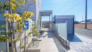 Un bâtiment moderne doté d’une passerelle couverte, d’un petit arbre et d’un portail en métal.