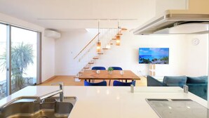 Une cuisine moderne avec un coin repas, un escalier et un espace de vie équipé d’un téléviseur.