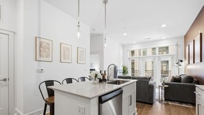 Une cuisine moderne dotée d’un îlot central, d’un coin repas avec des chaises et d’un espace de vie comprenant un canapé et une table basse.