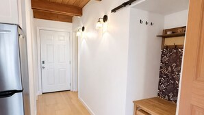 Ett kök med träbjälkar, ett kylskåp, en lampa och en dörr.