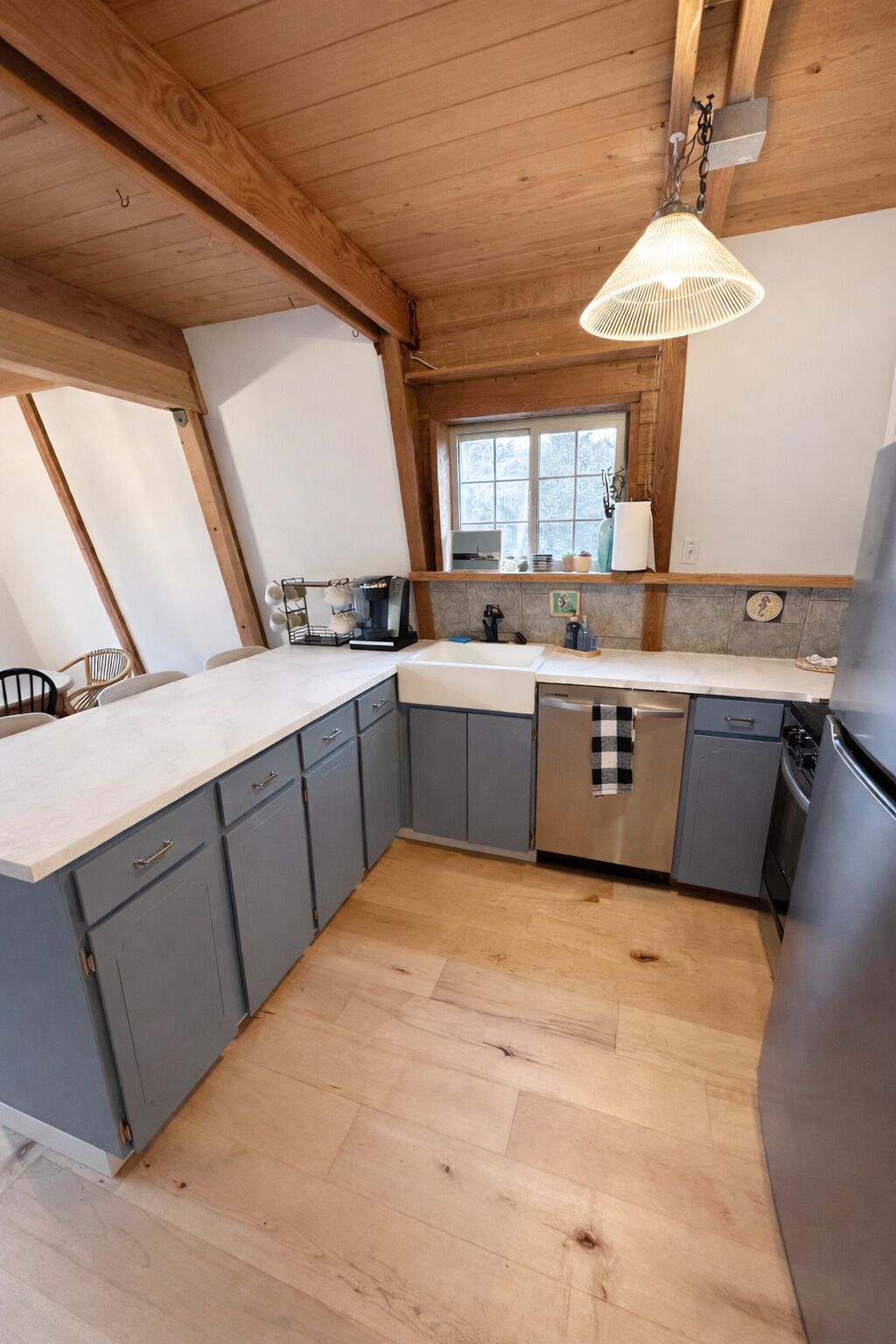 A kitchen with wooden beams, a window, and a dishwasher.