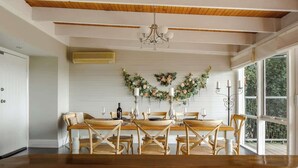 A dining area with a wooden table and chairs, a chandelier, and a floral wall decoration. - Seednest Treehouse Spectacular Mountain View (Monbulk)