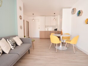 A modern living room with a grey sofa, yellow chairs, and a small round table. - 1-Br with Terrace – Carré d’Or, Walking Distance to the Beaches (Cannes)