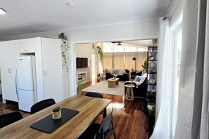 A modern kitchen with white cabinets, a wooden dining table, and a black chair.
