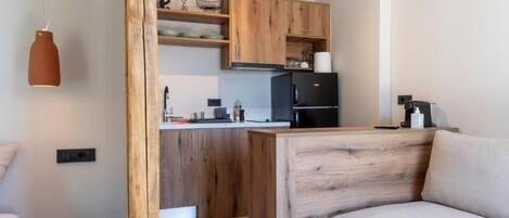 A modern kitchen with wooden cabinets, a black refrigerator, and a small dining table.