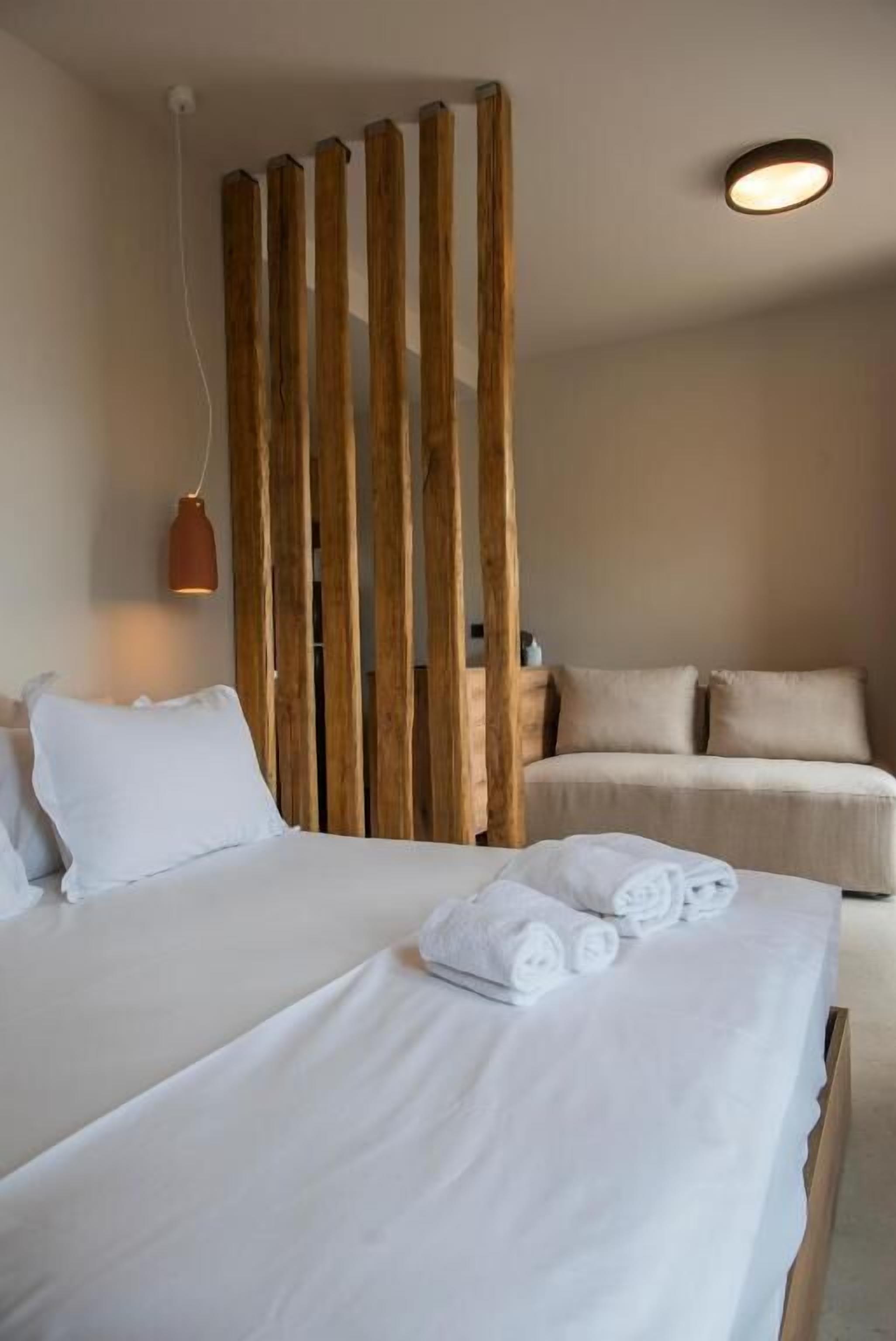 Een hotelkamer met twee bedden, een houten scheidingswand en een ronde plafondlamp.