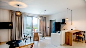 Een moderne hotelkamer met een zithoek, een televisie en een keukenblad.