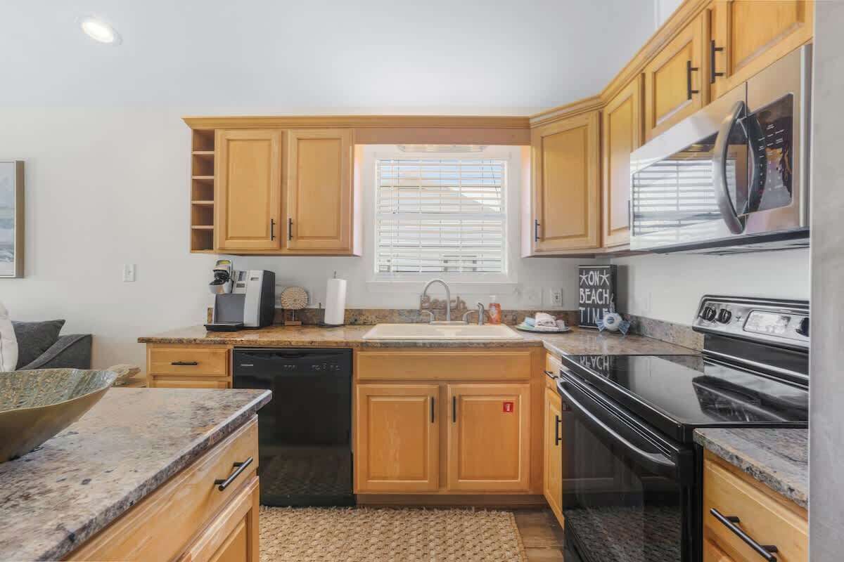 A kitchen with wooden cabinets, a built-in oven, a microwave, and a sink.
