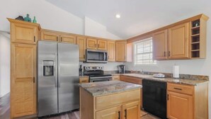 A modern kitchen with wooden cabinets, stainless steel appliances, and a granite countertop. - Walk to Beach | Pool, Deck & Easy Gulf Shores Stay (Gulf Shores)