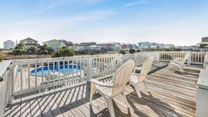 A wooden deck with a pool, white chairs, and a white fence. - Walk to Beach | Pool, Deck & Easy Gulf Shores Stay (Gulf Shores)