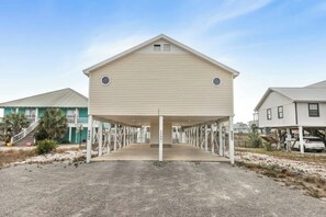 A beach house with a covered porch, a small window, and a number '1349' on the front. - Walk to Beach | Pool, Deck & Space to Unwind (Gulf Shores)