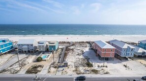 A coastal area with buildings, a road, and a beach. - Walk to Beach | Pool, Deck & Space to Unwind (Gulf Shores)
