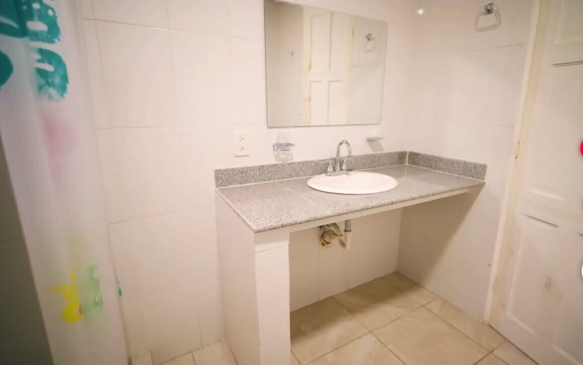 A bathroom with a white sink, a mirror above it, and a tiled floor.