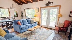 A spacious living room with a blue sofa, wooden flooring, and a wooden ceiling. - Sunriver retreat w/ hot tub, SHARC passes, pet-friendly (Sunriver)