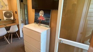 Ein Zimmer mit Schreibtisch, weißem Schminktisch, Wand-Fernseher und einer Schiebetür.