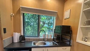 Eine kompakte Küche mit Spüle, Kaffeemaschine, Mikrowelle und Kühlschrank.