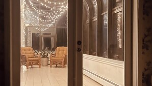 A room with a sliding glass door leading to a dining area with two chairs and a table.
