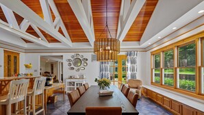 A spacious dining area with a long table, wooden chairs, and a hanging light fixture.
