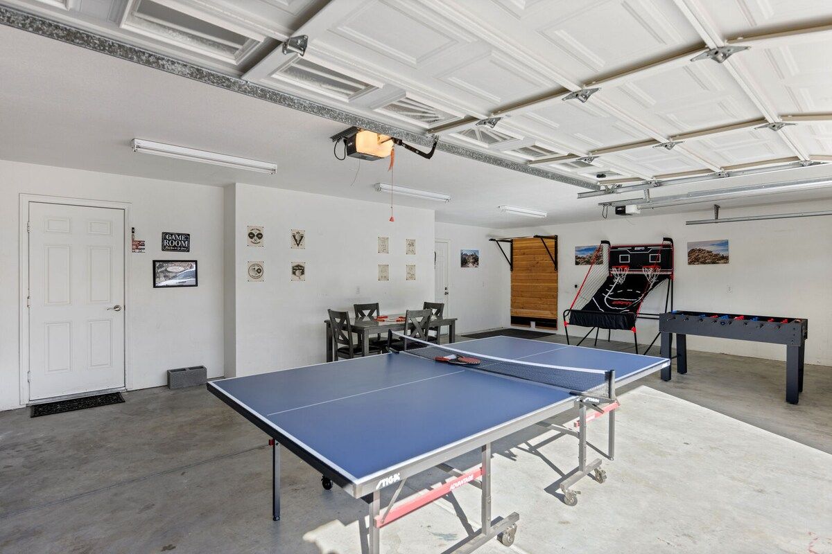 A room with two ping pong tables, a foosball table, and a door with a 'Game Room' sign.
