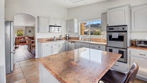 A modern kitchen with white cabinetry, granite countertops, and stainless steel appliances. - Casa Selecta - Hot Tub, Game Room & Pool (Yucca Valley)