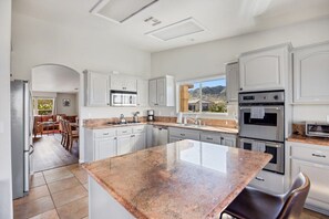 Una cocina moderna con armarios blancos, encimeras de granito y electrodomésticos de acero inoxidable.