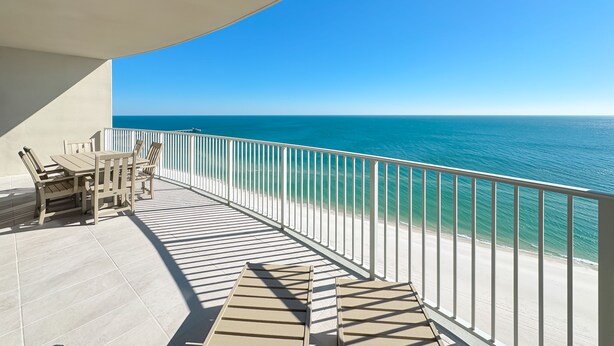 Un balcon avec vue sur l’océan, une table avec des chaises et une rambarde.