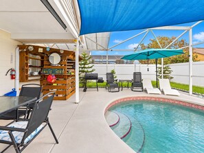 Ein Poolbereich mit Grill, Liegestühlen und einer überdachten Terrasse.