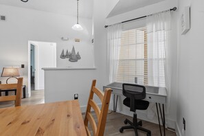 A modern, well-lit room with a wooden dining table, a black office chair, and a window with blinds. - Your Own 3BR Private Home w/ Heated Pool • Quiet Family Retreat Near Disney (Kissimmee)