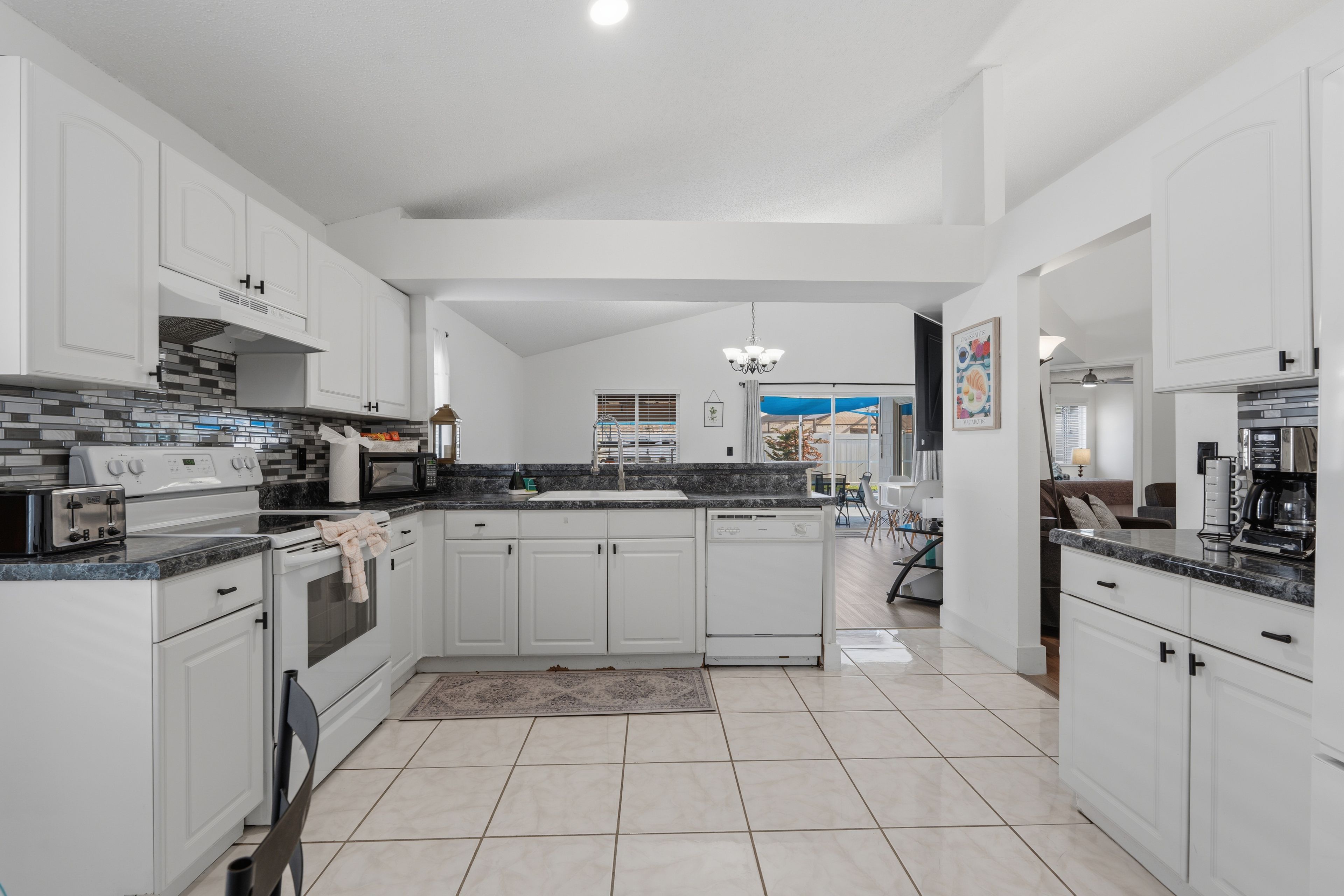 A spacious kitchen with white cabinetry, a tiled floor, and modern appliances.