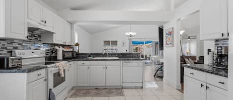 A spacious kitchen with white cabinetry, a tiled floor, and modern appliances.