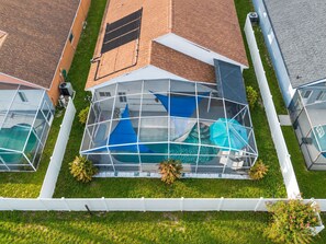 A residential property with a large glass-enclosed swimming pool, a covered patio area, and a brick roof. - Your Own 3BR Private Home w/ Heated Pool • Quiet Family Retreat Near Disney (Kissimmee)