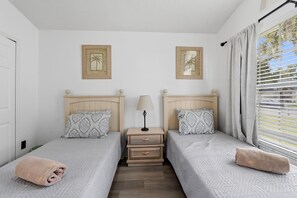 A twin room with two beds, a nightstand, a lamp, and two framed pictures on the wall. - Your Own 3BR Private Home w/ Heated Pool • Quiet Family Retreat Near Disney (Kissimmee)