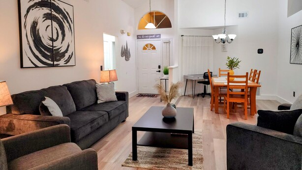 Ett modernt vardagsrum med en mörkgrå soffa, ett svart soffbord och en matplats med trästolar och ett bord.