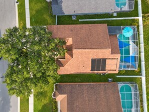 A residential area with a house featuring a sloped roof, a visible chimney, and a large tree in the foreground. - Your Own 3BR Private Home w/ Heated Pool • Quiet Family Retreat Near Disney (Kissimmee)