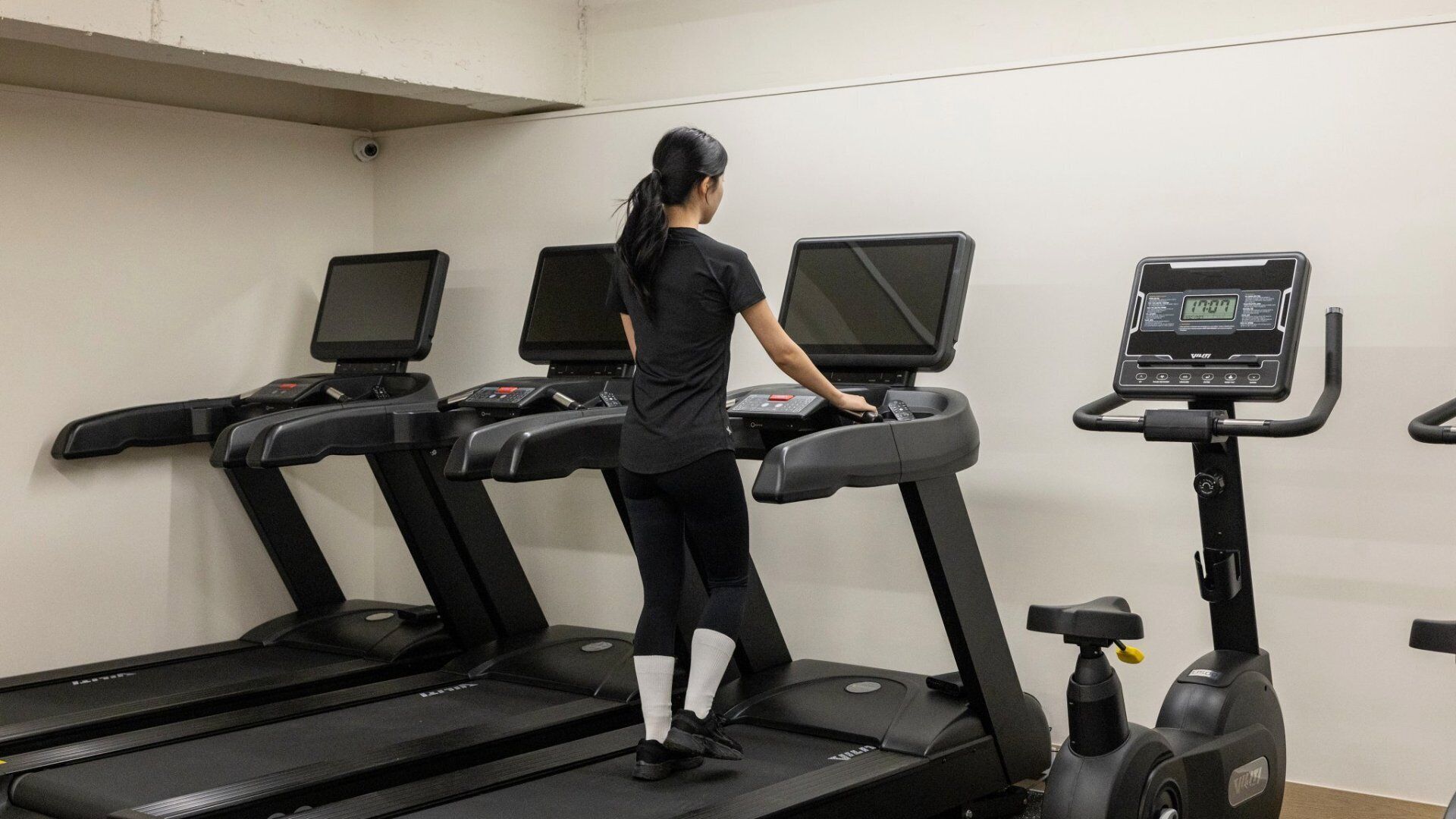 A person using a treadmill in a gym with multiple treadmills and a stationary bike.
