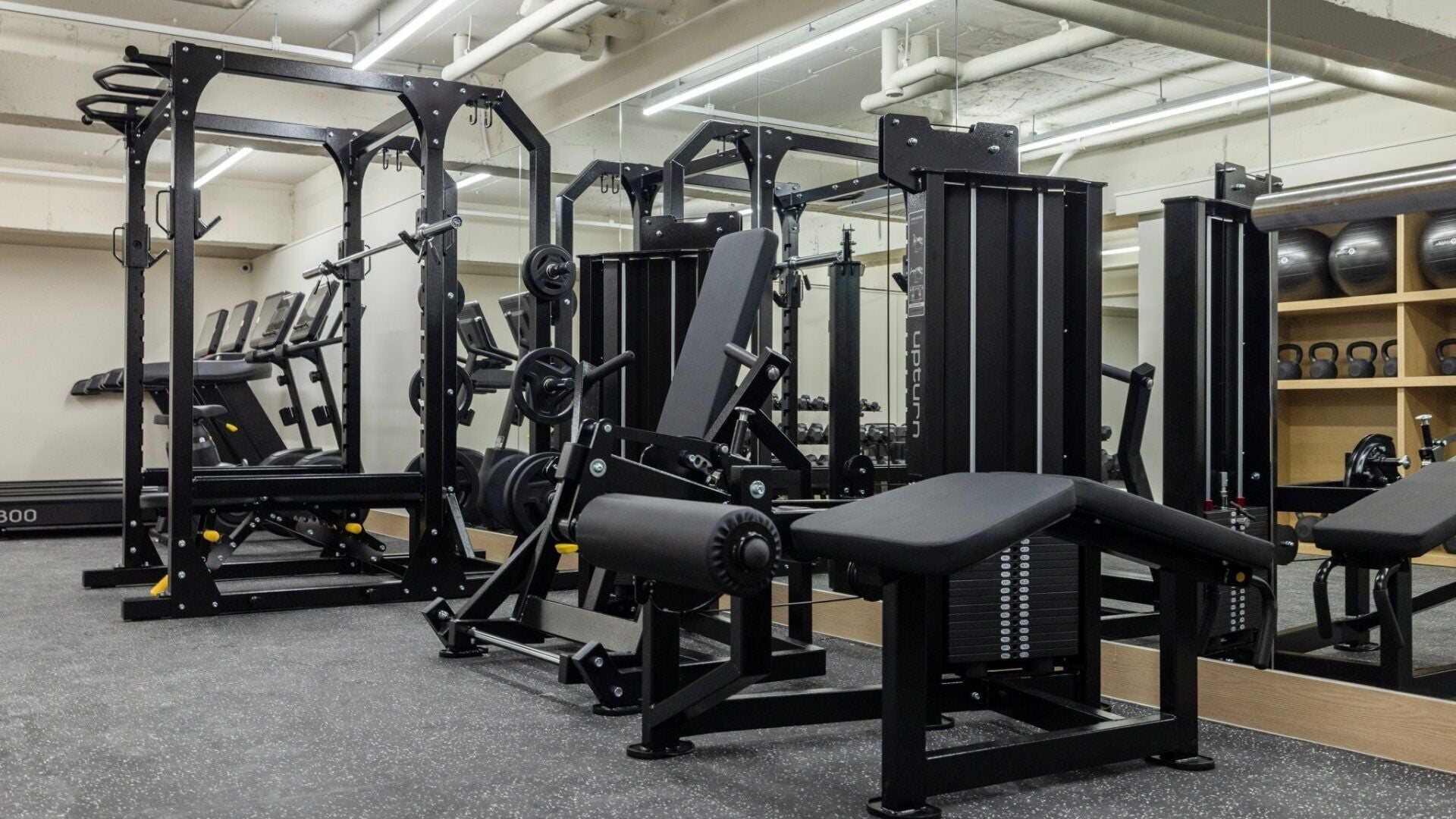 A gym with various weightlifting equipment, including benches and squat racks.