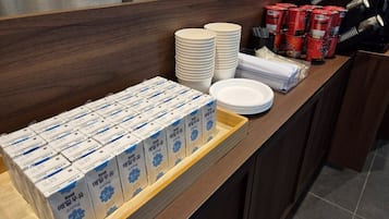 Una mesa de buffet con platos, recipientes y latas de condimentos apilados.