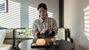 A person seated at a table with a traditional Japanese meal setup, including a wooden tray, bowls, and a small vase with flowers. - Anook Hotel & Spa Seoul Jongno Anguk 2nd (Seoul)