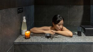 A person in a bathtub with a bottle and candle on the edge. - Anook Hotel & Spa Seoul Jongno Anguk 2nd (Seoul)