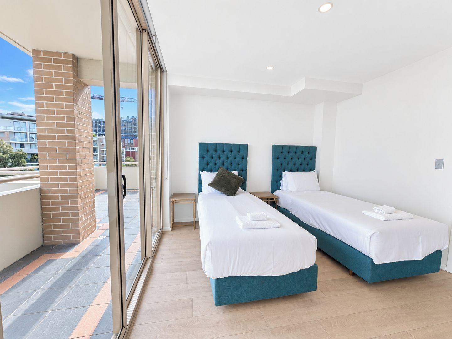 Habitación de hotel con dos camas, un balcón y vista a la ciudad.