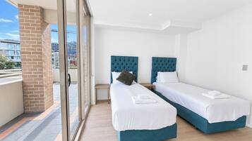 Habitación de hotel con dos camas, un balcón y vista a la ciudad.