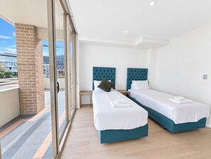 A hotel room with two beds, a balcony, and a view of the city. - Spacious City View 3BR Loft Apartment | Parking*2 (Mascot)