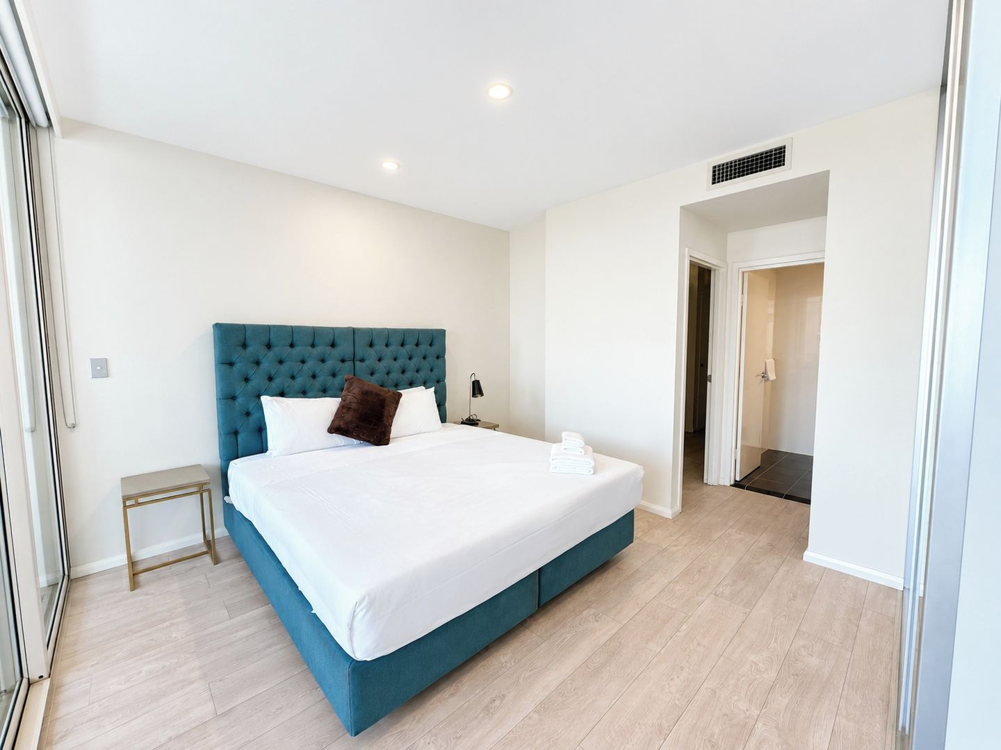 Ein modernes Hotelzimmer mit einem großen Bett, einem Nachttisch und einem begehbaren Kleiderschrank.