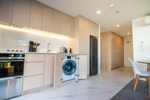Een moderne keuken met inbouwapparatuur, een wasmachine en een eethoek met een stoel.