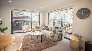 A modern living room with a sofa, armchairs, a coffee table, and a dining area. - Inner City Apartment - Prime location! (Christchurch)